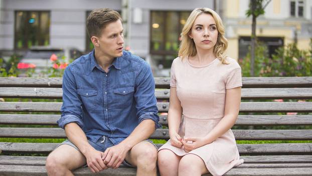 Man and woman breaking up on bench in park, conflict in relationship, problem