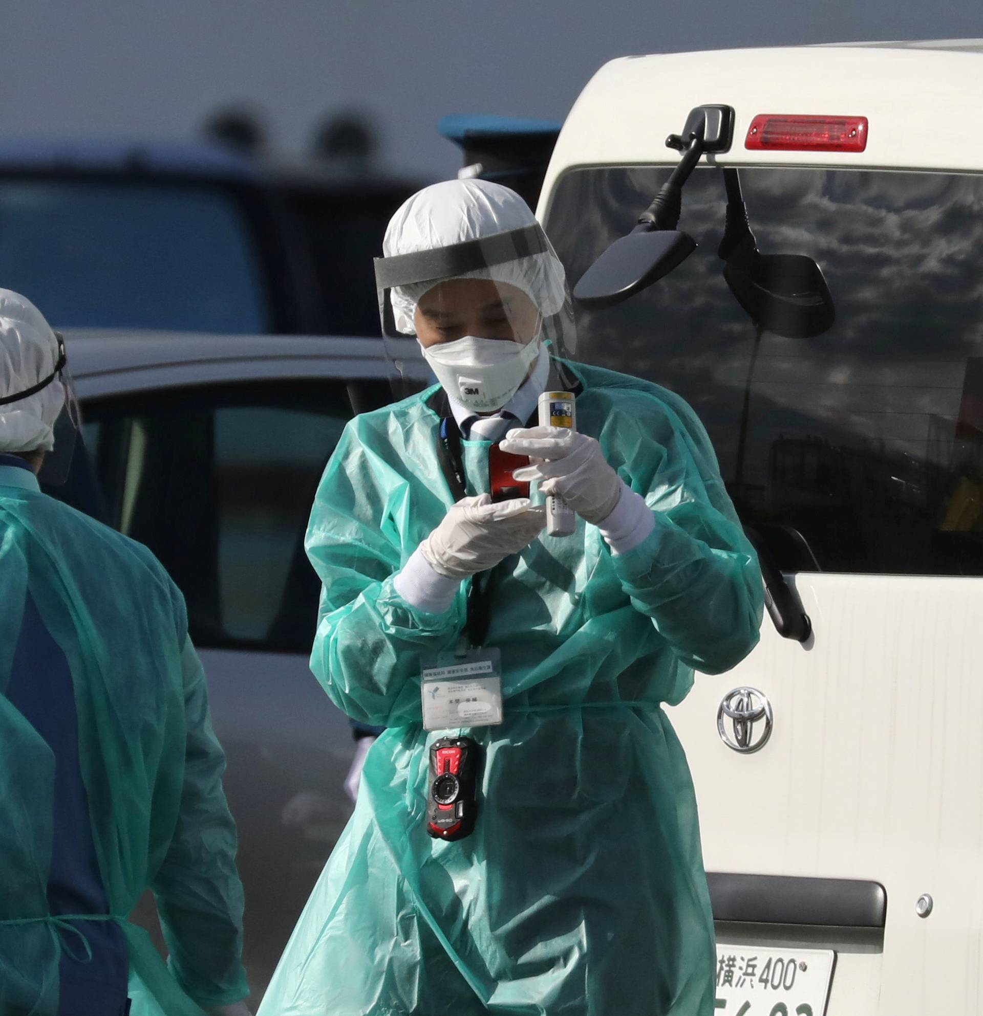 Health officials dressed in protective gear are seen near the cruise ship Diamond Princess at Daikoku Pier Cruise Terminal in Yokohama