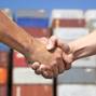 Two,Business,Man,Handshaking,Before,Stack,Of,Containers