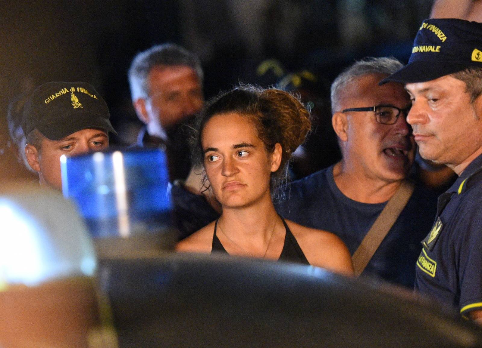 Carola Rackete, the 31-year-old Sea-Watch 3 captain, is escorted off the ship by police and taken away for questioning, in Lampedusa