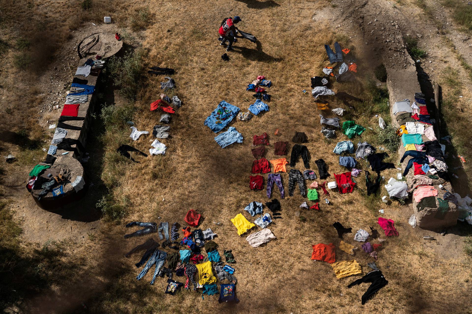 Asylum-seeking migrants wait to be processed under the international bridge in Del Rio, TX