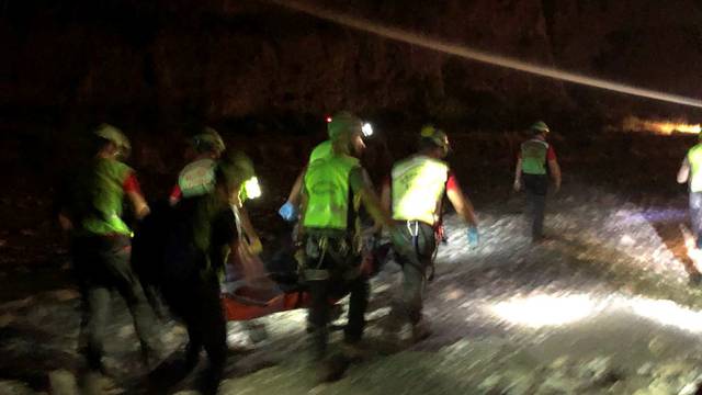 Alpine rescue workers carry a body after several people were killed in a mountain gorge flooding, in the municipality of Civita