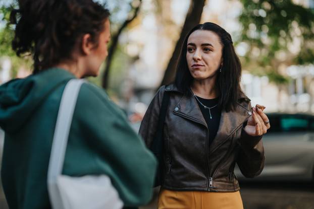 Two friends having a conversation outdoors on a sunny urban day