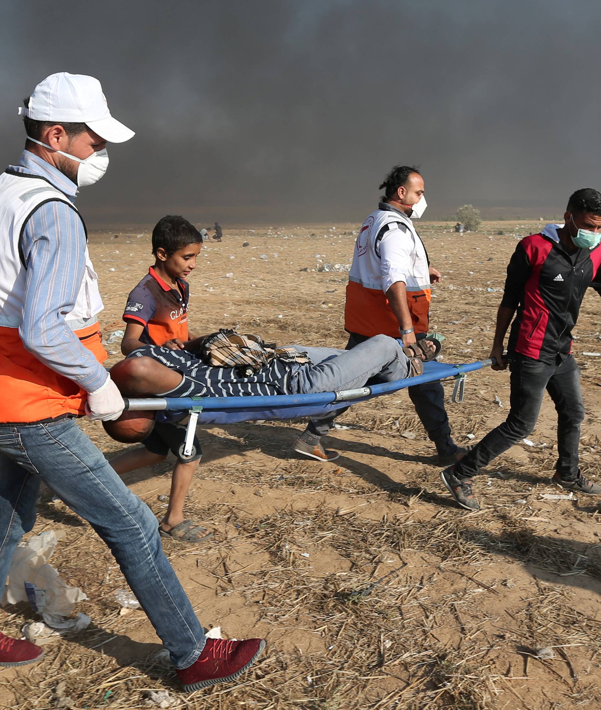 Wounded Palestinian demonstrator is evacuated after inhaling tear gas fired by Israeli troops during a protest marking the 70th anniversary of Nakba, at the Israel-Gaza border in the southern Gaza Strip