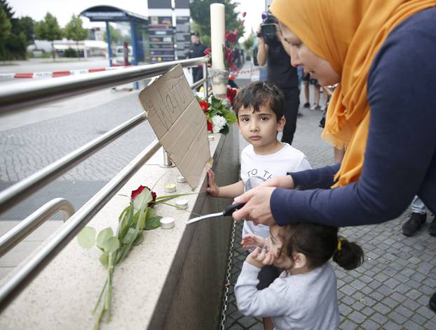 Woman lights candles on wall near Olympia shopping mall in Munich