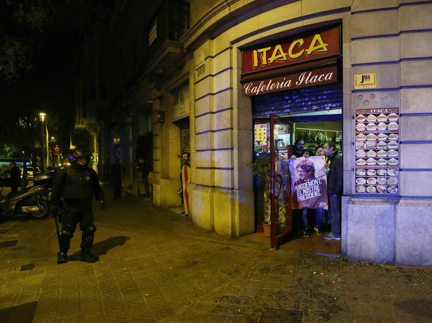A protestor holds up a poster of former Catalan president Carles Puigdemont in the entrance of a cafe during skirmishes with police after Puigdemont was detained in Germany,  in Barcelona