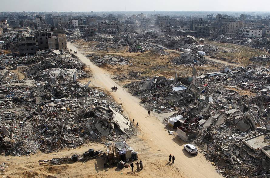 Palestinians walk past the rubble of buildings destroyed during the Israeli offensive in Rafah