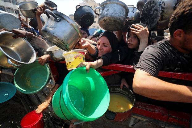 Palestinians wait to receive food from a charity kitchen, in Gaza City