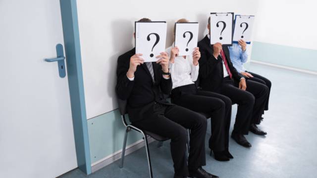 Businesspeople Hiding Behind Question Mark Sign