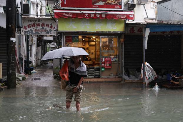 A man holds an umbrella as he wades through a flooded area, in the aftermath of Super Typhoon Ragasa in Hong Kong