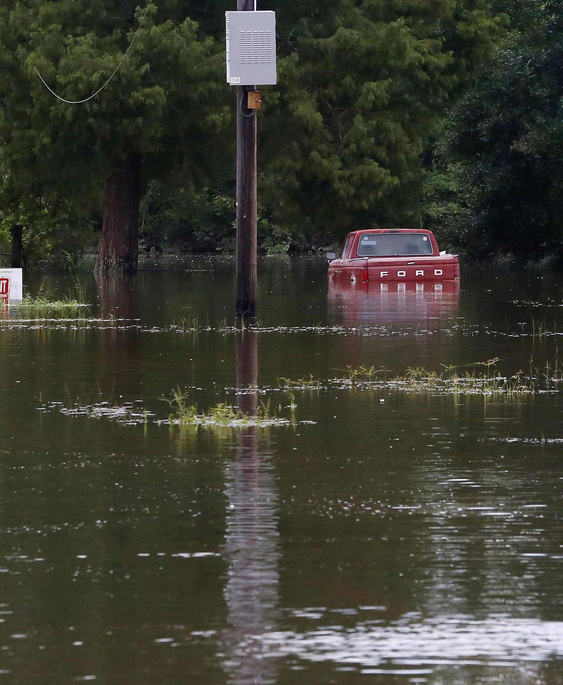 A vehicle is seen on a flooded street in Prairieville, Louisiana