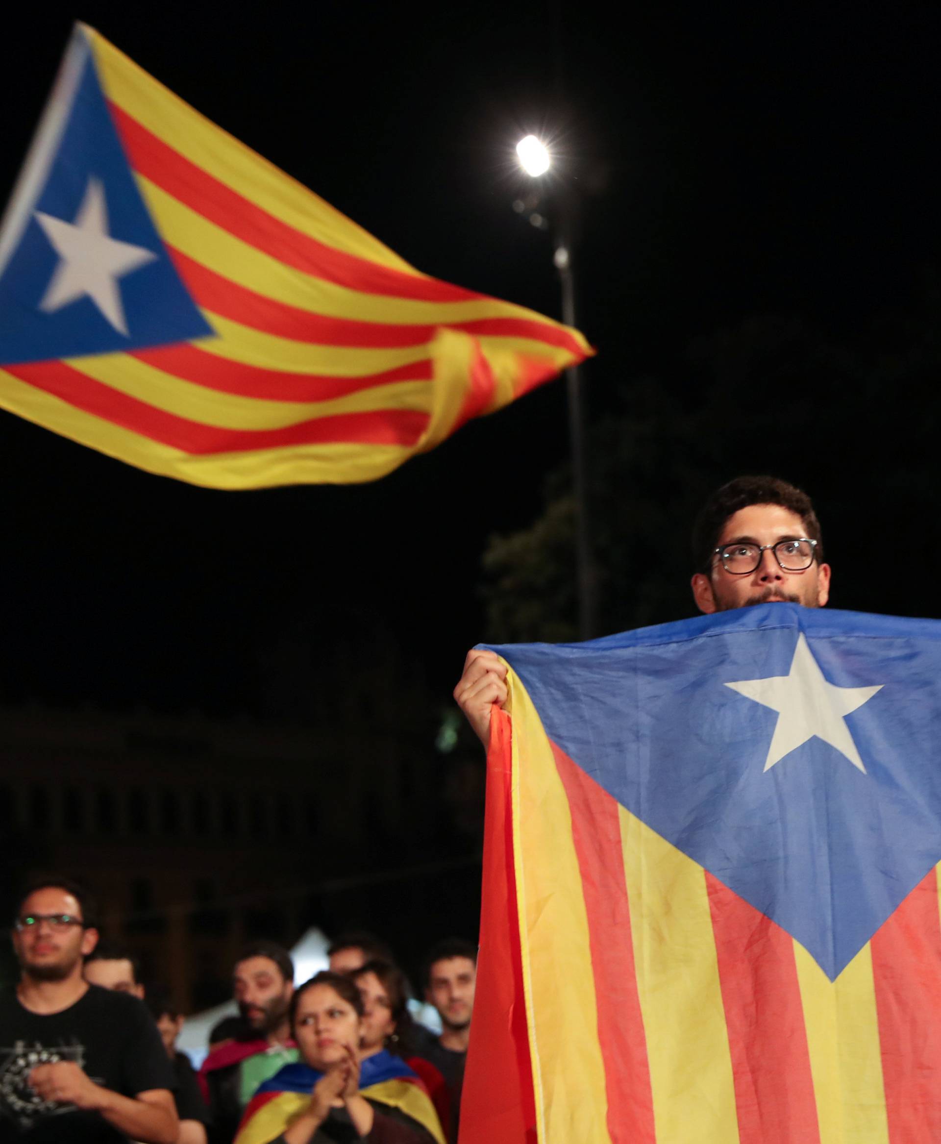 A man holds an Estelada (Catalan separatist flag) as people gather at Plaza Catalunya after voting ended for the banned independence referendum, in Barcelona