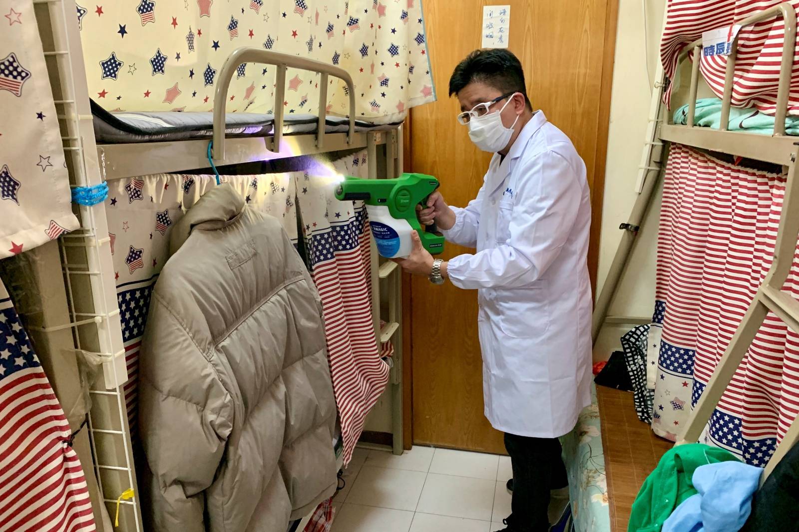 Man demonstrates spraying an antomicrobial coating at a bedspace apartment in Hong Kong