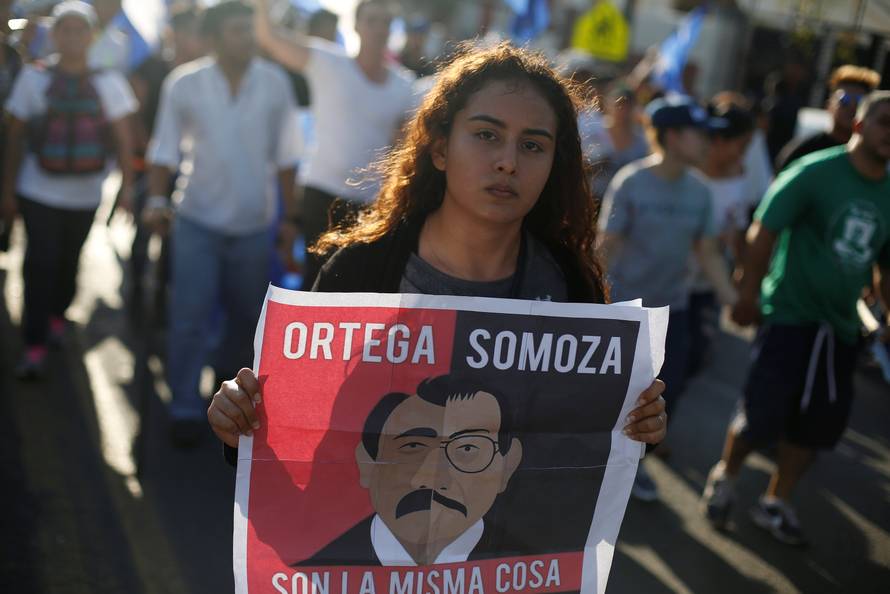 A demonstrator holds a sign showing Nicaraguan President Daniel Ortega and former President Anastasio Somoza during a protest against police violence and the government of President Ortega in Managua