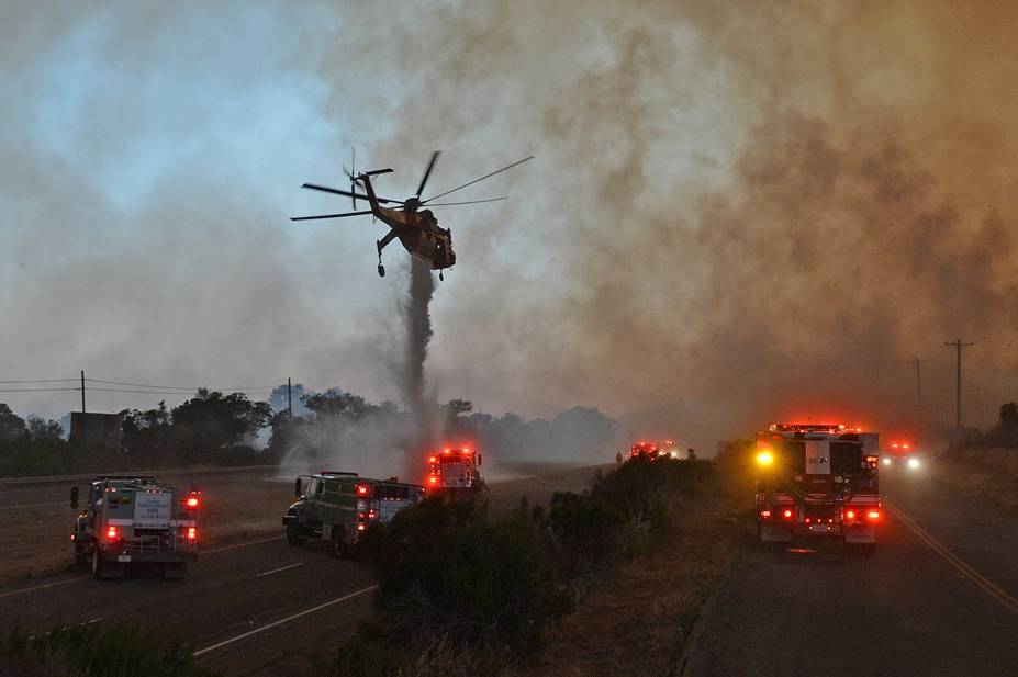 Handout photo of a sky crane helicopter making a drop as the so-called Sherpa Fiire burns on the divider of Highway 101 at El Capitan State Beach in Santa Barbara