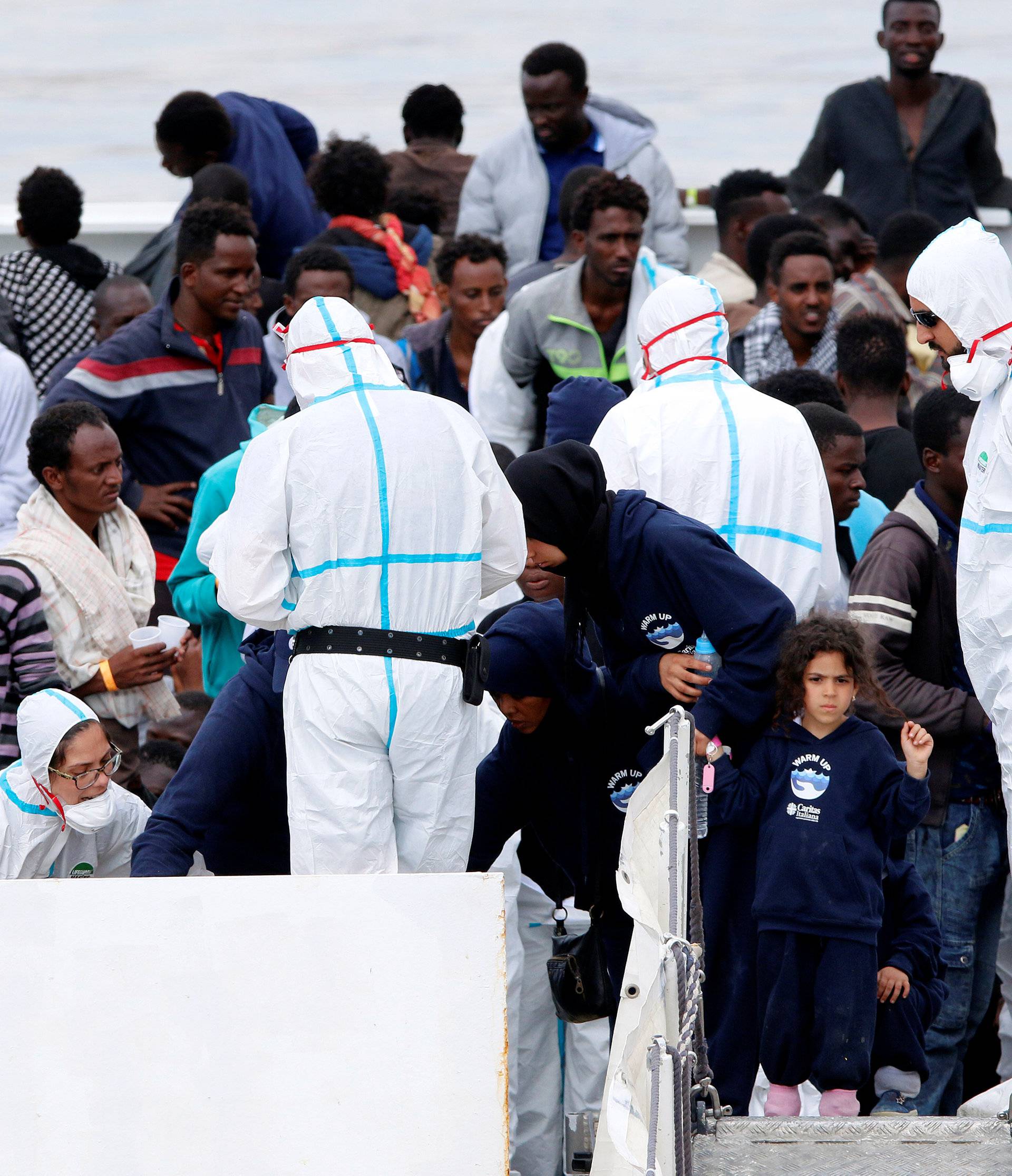 Migrants wait to disembark the Italian coast guard vessel "Diciotti" as they arrive at the port of Catania