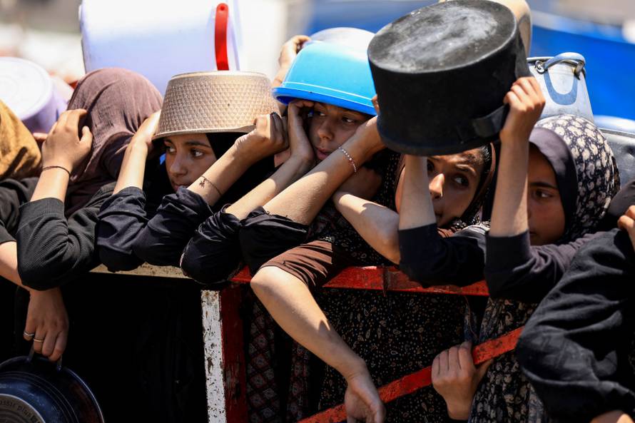 Palestinians wait to receive food from a charity kitchen, in Gaza City