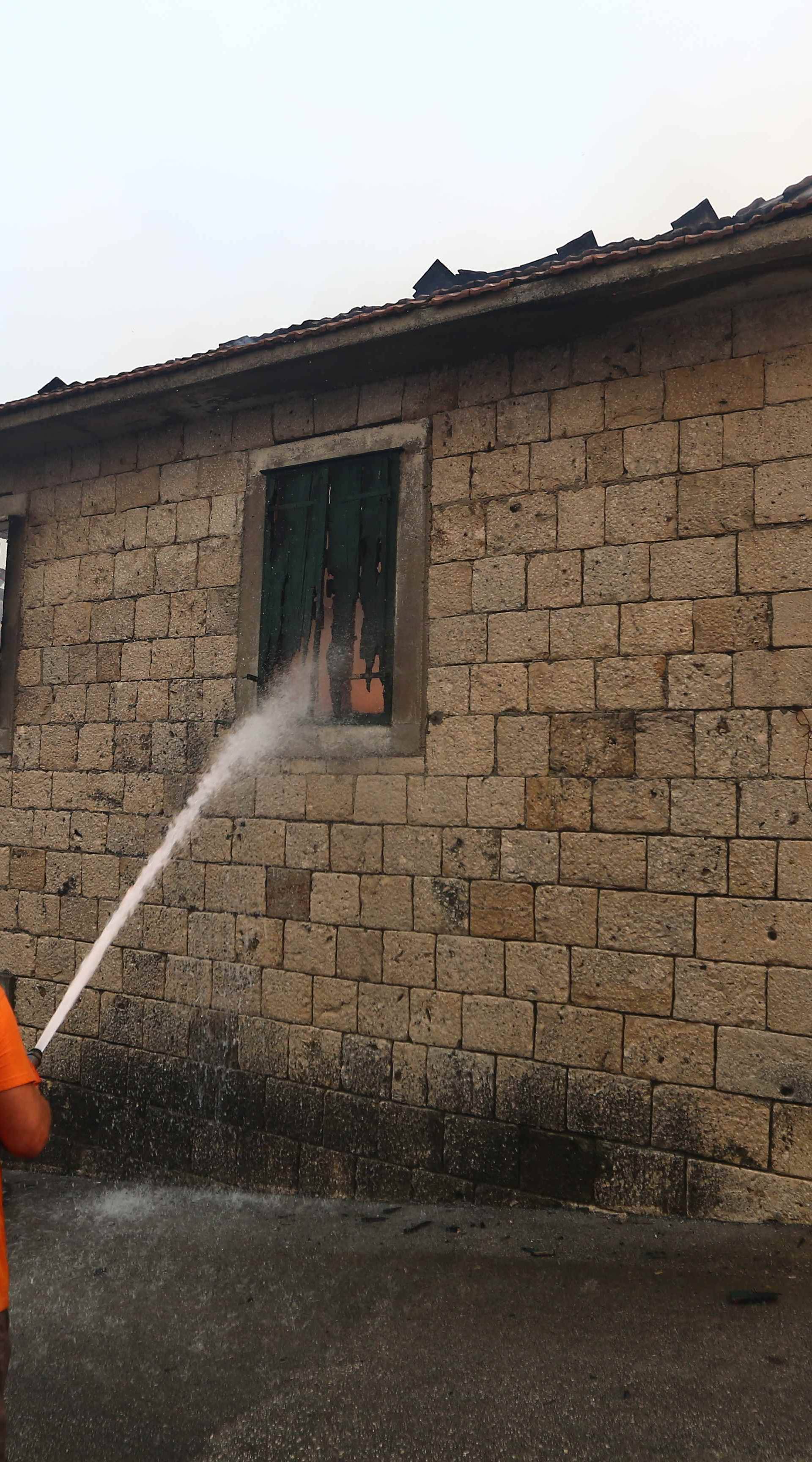 A local resident tries to extinguish a wildfire in the village of Mravince near Split