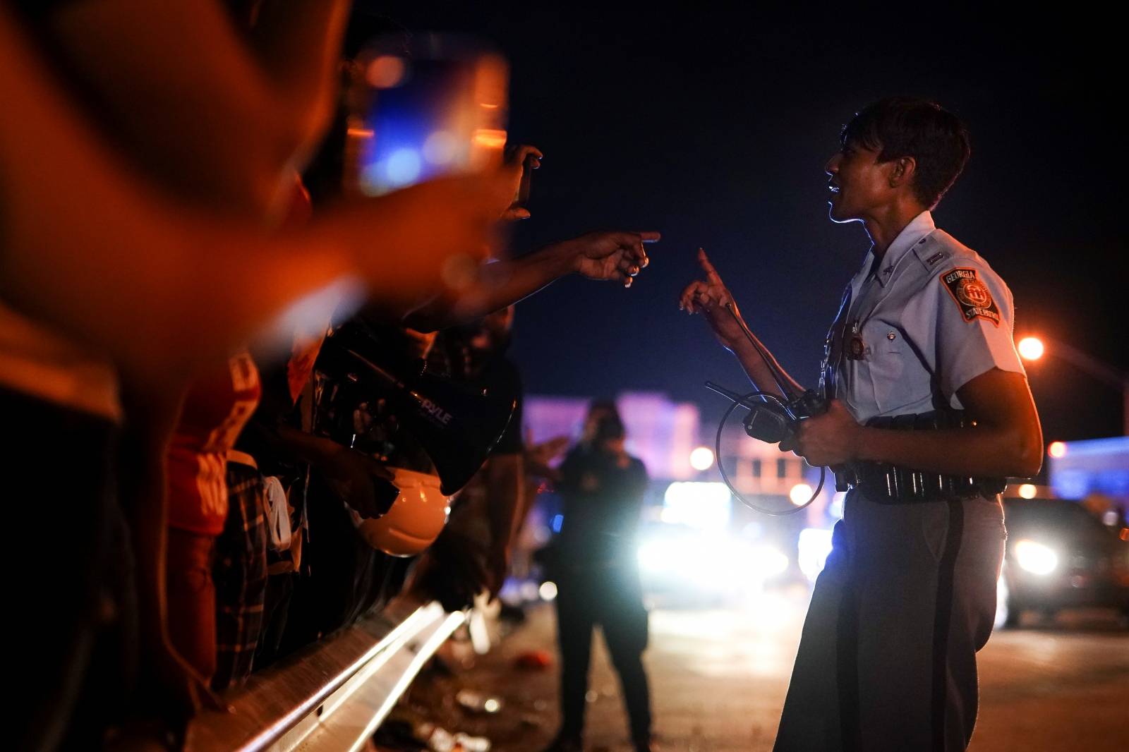Protesters film an interaction with a Georgia State Patrol officer during a rally against racial inequality and the police shooting death of Rayshard Brooks, in Atlanta