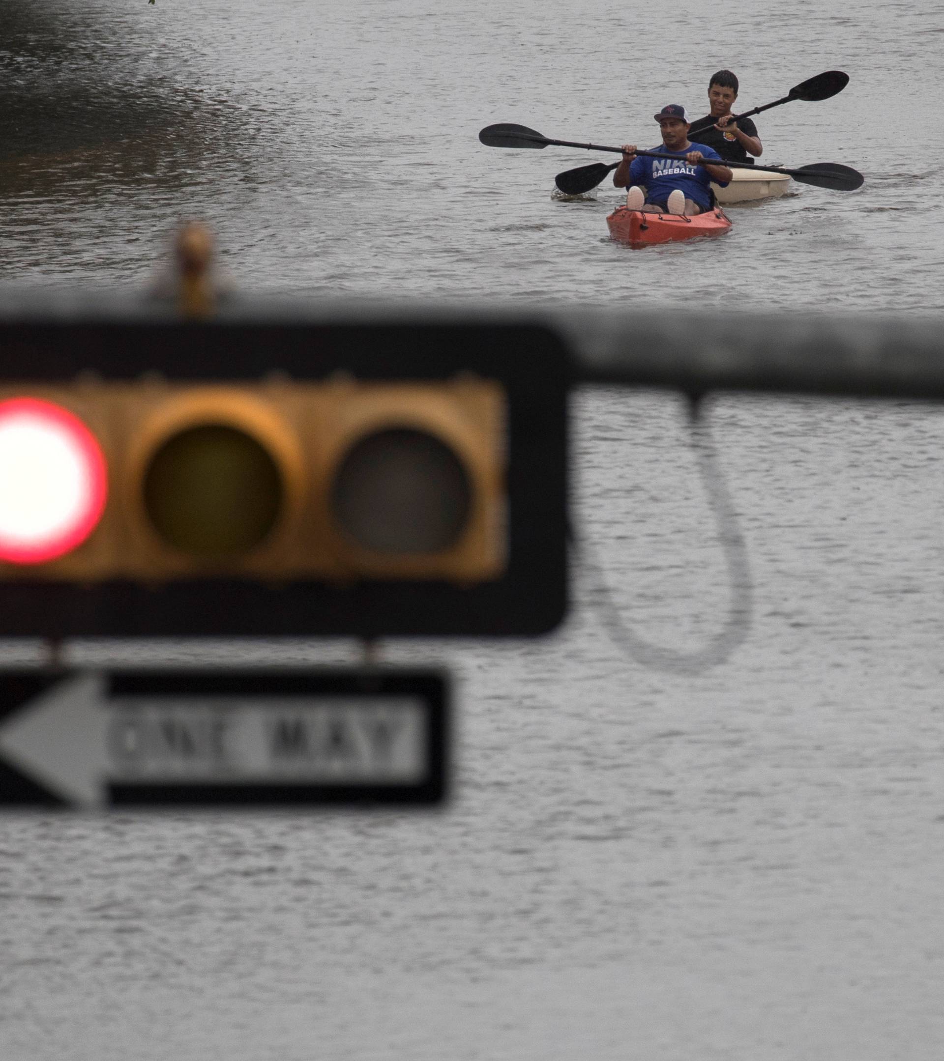 Men use kayaks to get through an intersection after heavy rain from Hurricane Harvey flooded Pearland, in the outskirts of Houston