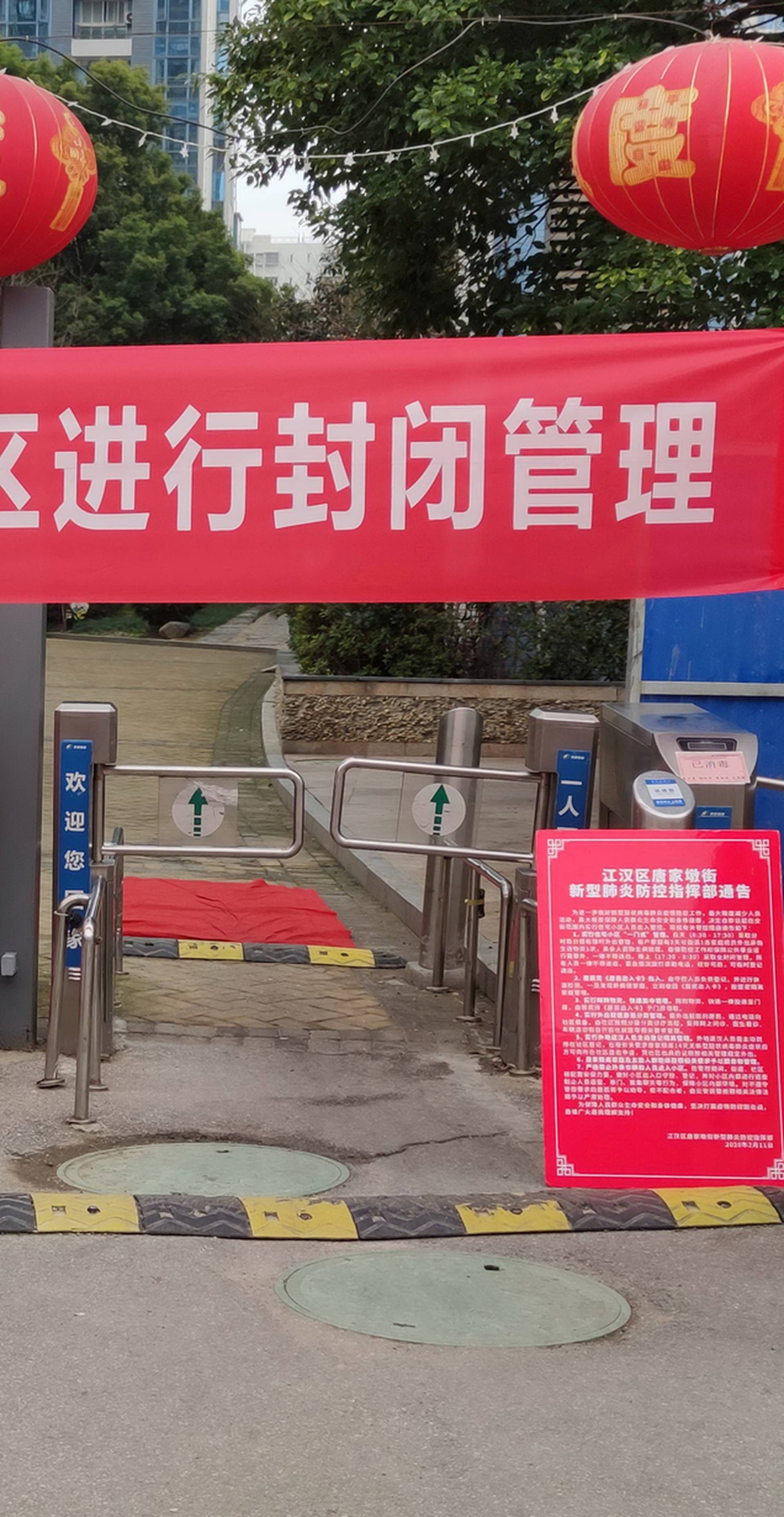 FILE PHOTO: Workers in protective suits are seen at a checkpoint for registration and body temperature measurement, at an entrance to a residential compound in Wuhan