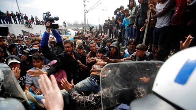 Migrants and refugees scuffle with Greek police after they tried to push a train carriage through a police bus on rail tracks leading to Macedonia at a makeshift camp at the Greek-Macedonian border near the village of Idomeni