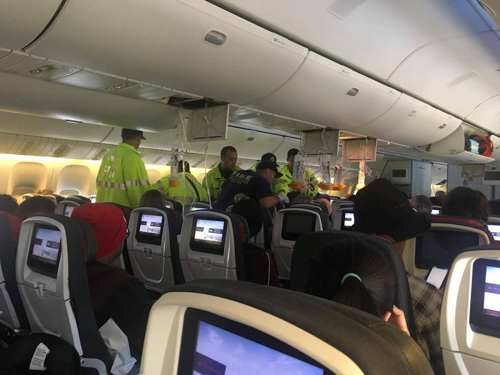 Emergency workers assist passengers of Air Canada AC 33 flight, which diverted to Hawaii after turbulence, at Honolulu airport