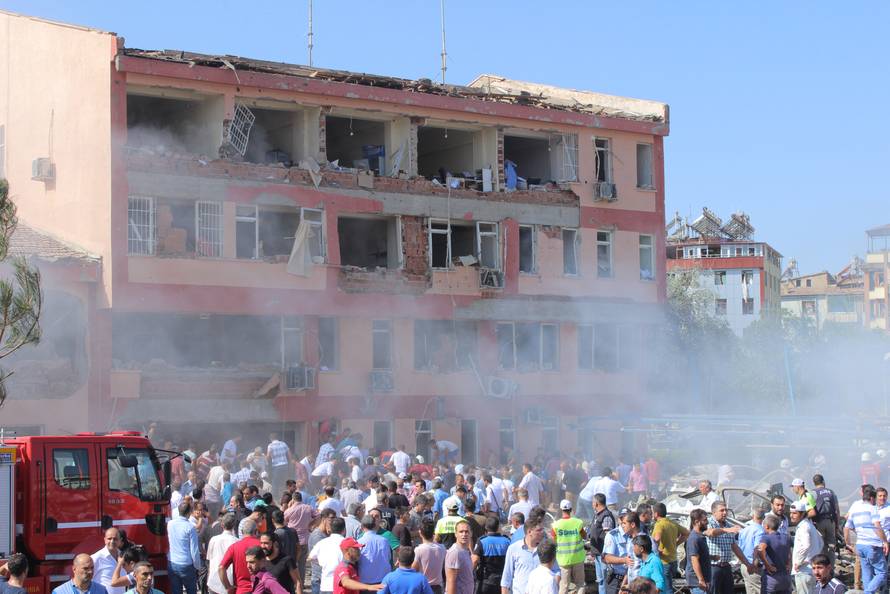 People rush to the blast scene after a car bomb attack on a police station in the eastern Turkish city of Elazig