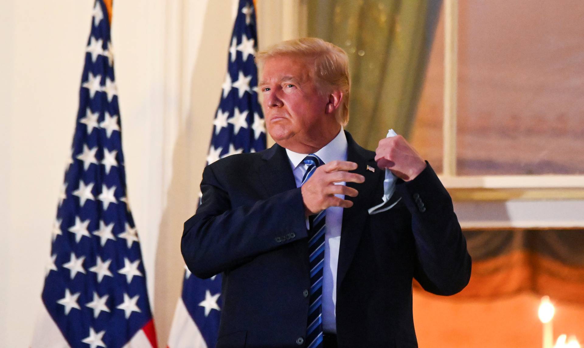 U.S. President Donald Trump pulls off his face mask as he returns to the White House after being hospitalized at Walter Reed Medical Center for coronavirus disease (COVID-19), in Washington