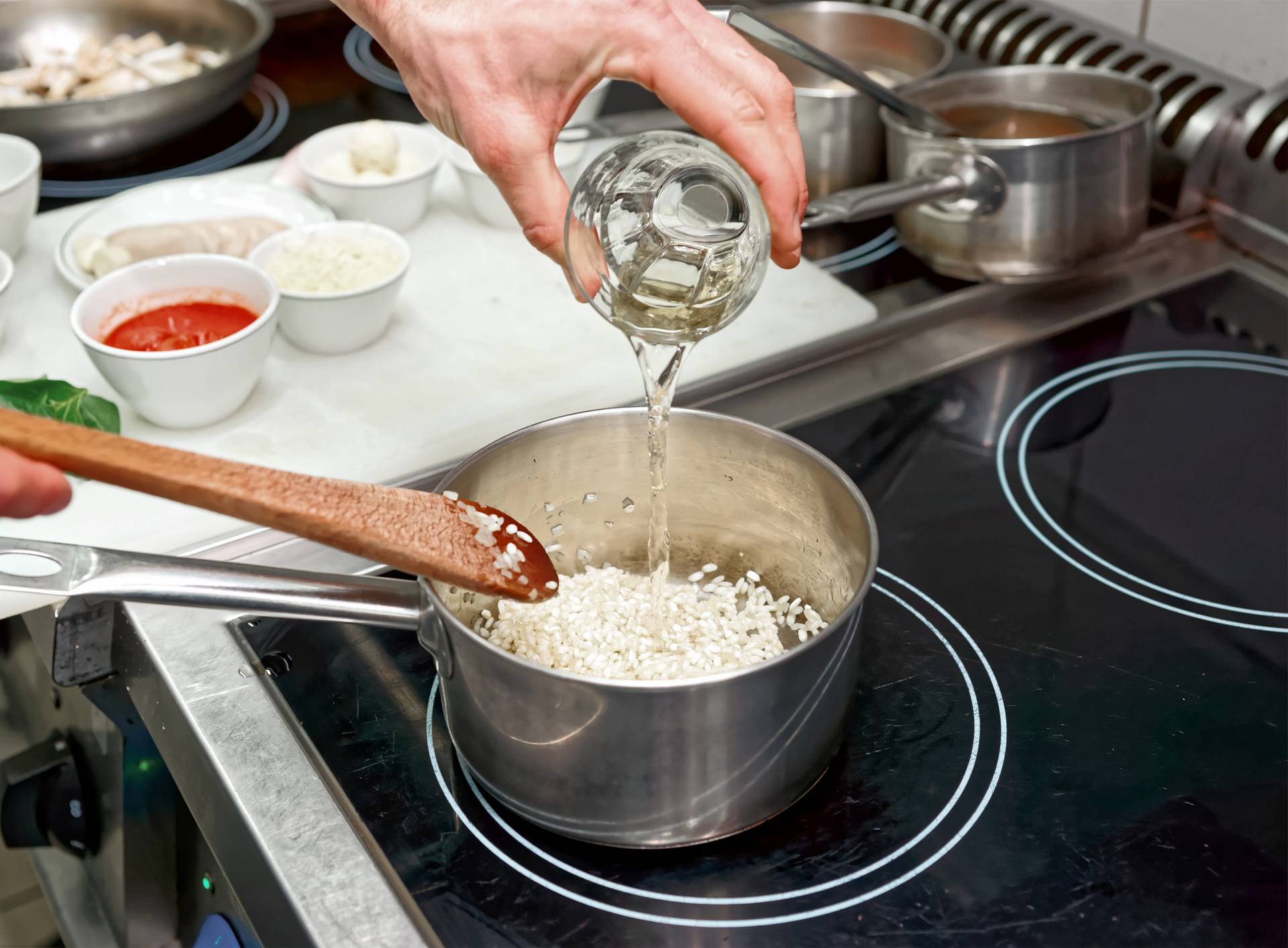 Chef is adding white wine to risotto