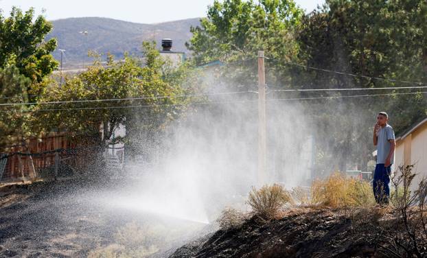 A man waters his yard near where the Hawk Fire is burning in Reno