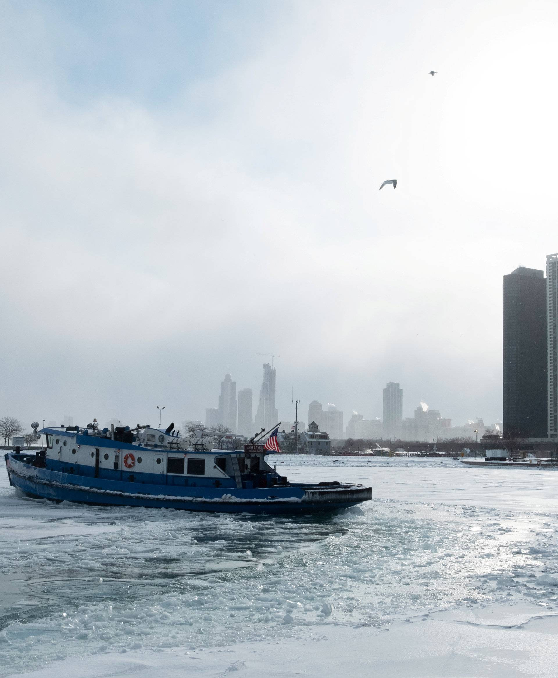 Icebreaker tugboat breaks ice through Lake Michigan in Chicago