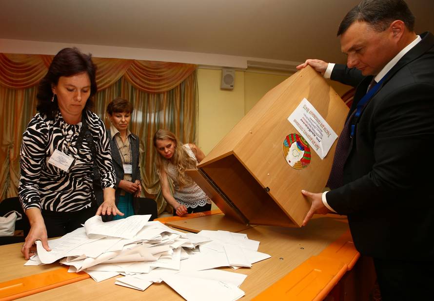 Members of the local electoral commission empty a box to count ballots at a polling station after a parliamentary election in Minsk