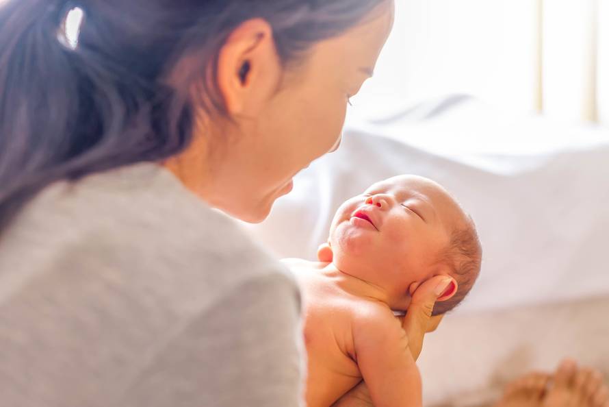 Young mother holding her little newborn baby girl, smiling with 