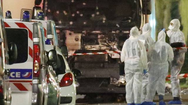 French police forces and forensic officers stand next to a truck that ran into a crowd celebrating the Bastille Day national holiday on the Promenade des Anglais killing at least 60 people in Nice