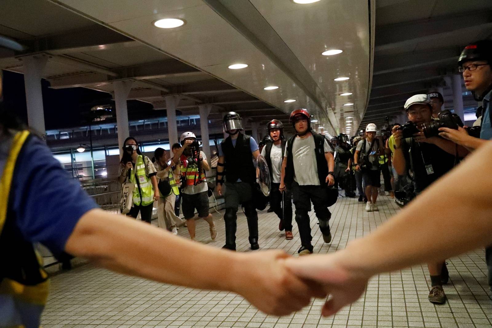 People hold hands to block the riot police outside a metro station, in Hong Kong