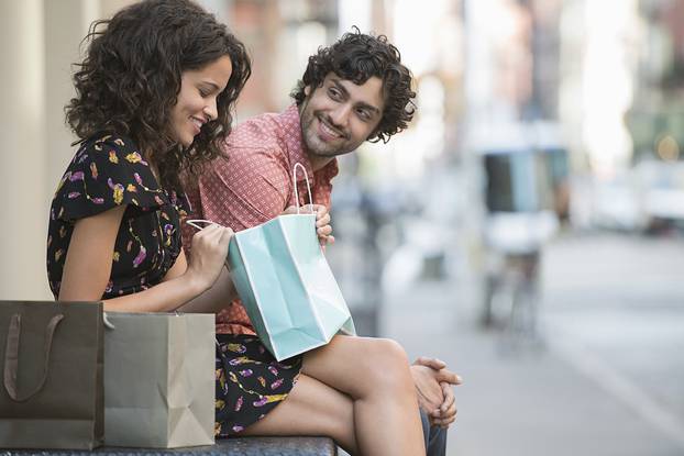 Young happy couple sitting outdoors during break in shopping