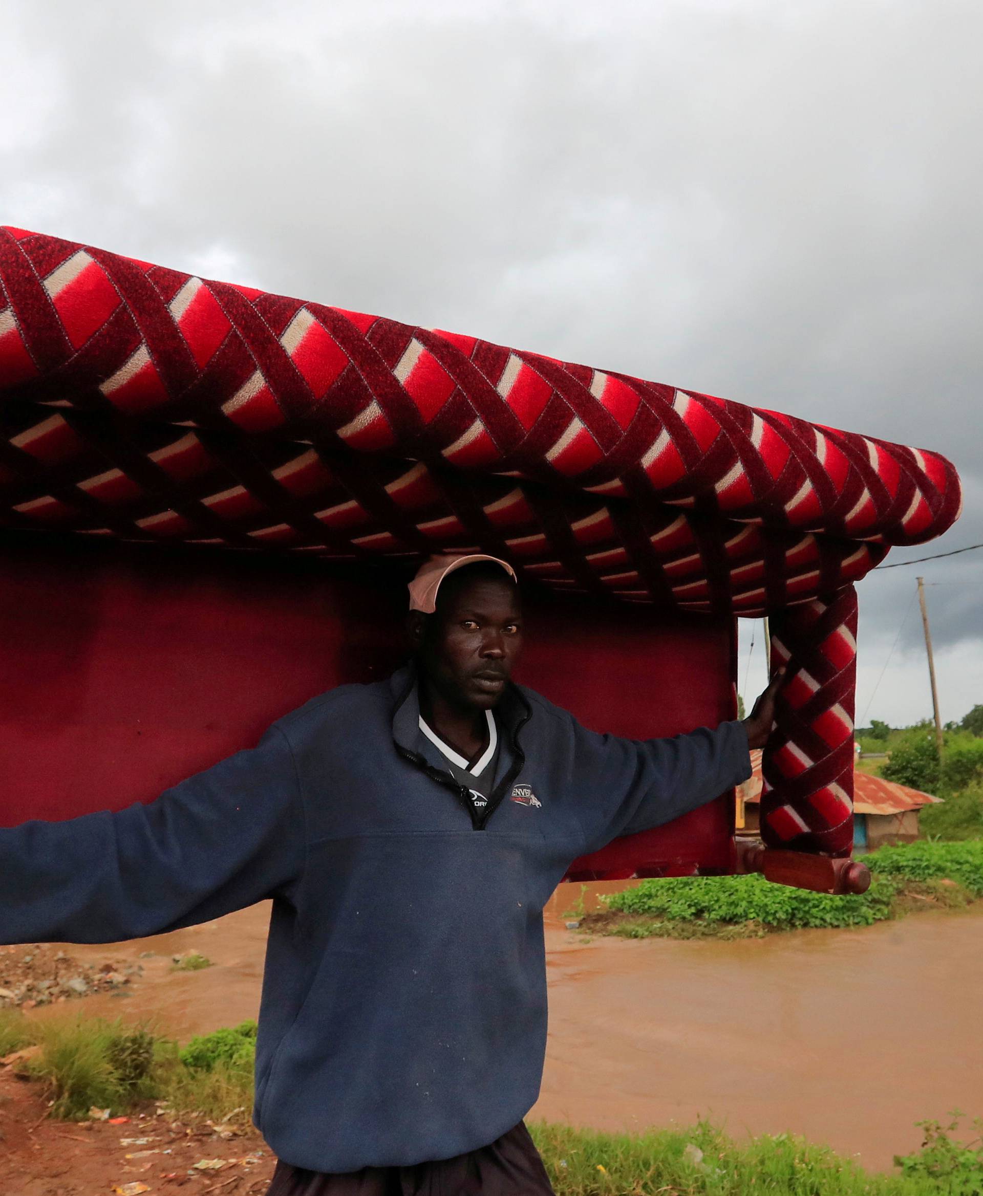A man carries a sofa as he evacuates from his home after River Nzoia burst its banks and due to the backflow  from Lake Victoria, in Nyadorera, Siaya County