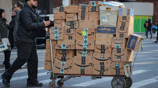 FILE PHOTO: A delivery person pushes a cart full of Amazon boxes in New York