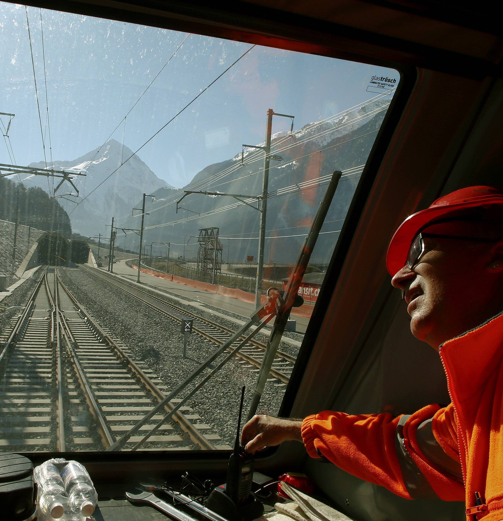 A railway worker looks out of the window of the drivers cabin of a test train in front of the nortern gate of the NEAT Gotthard Base Tunnel during a media visit, near the town of Erstfeld