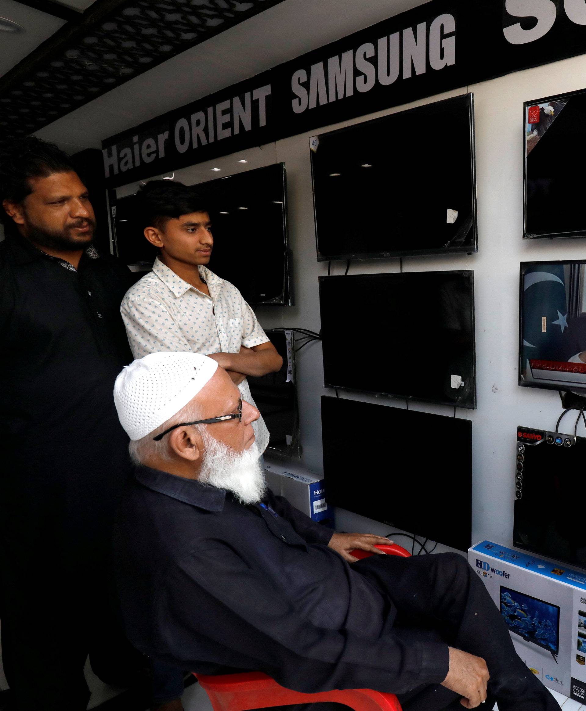 Shopkeepers watch the speech of Pakistani Prime Minister Imran Khan, after Pakistan shot down two Indian military aircrafts, at a shop selling television screens in Karachi