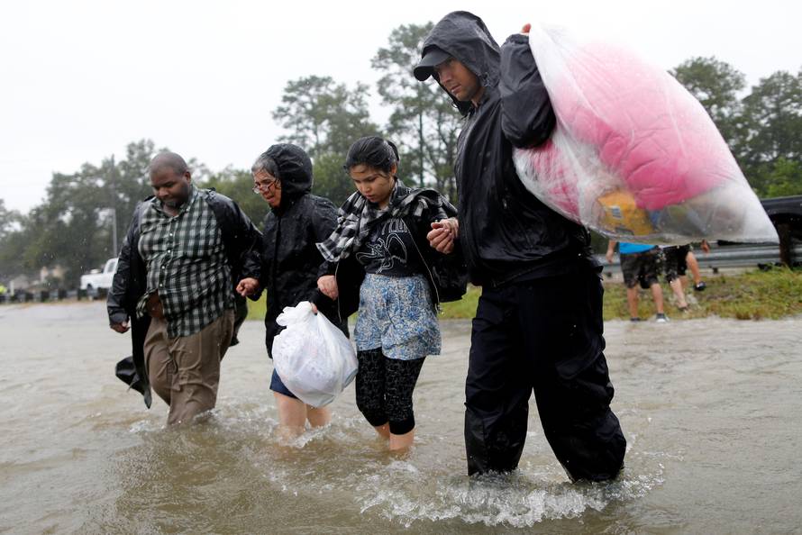 Residents wade through flood waters from tropical storm Harvey after being rescued in east Houston