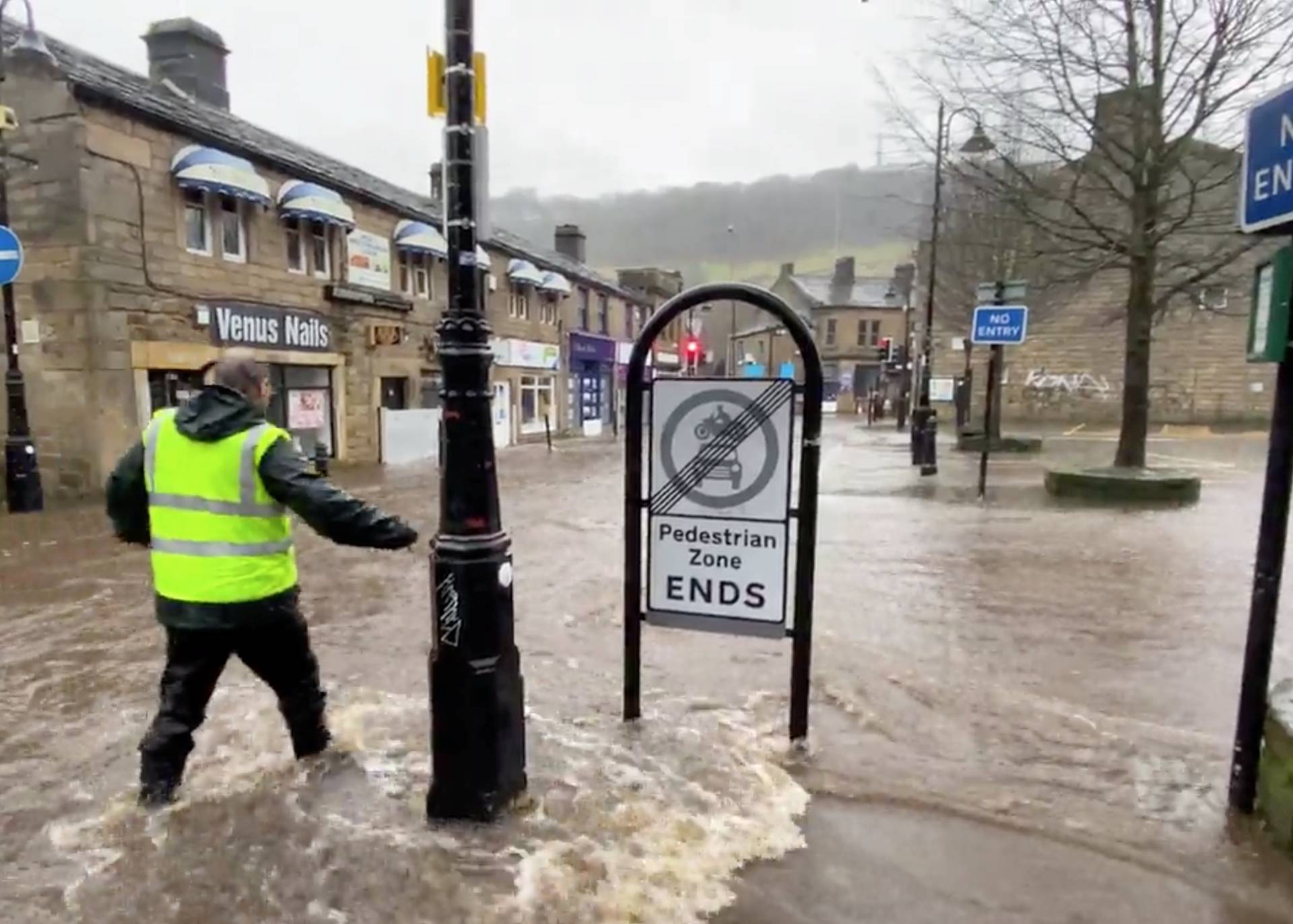 A man wades through a flooded street due to Storm Ciara in Hebden Bridge
