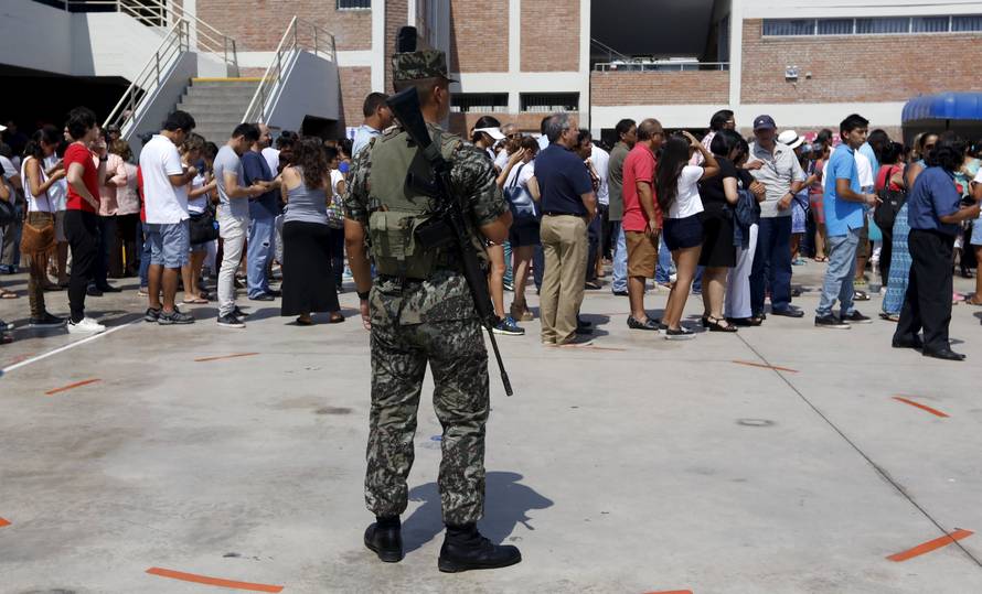 A soldier guards as people line up to vote during presidential election at a polling station in Lima's district of San Isidro