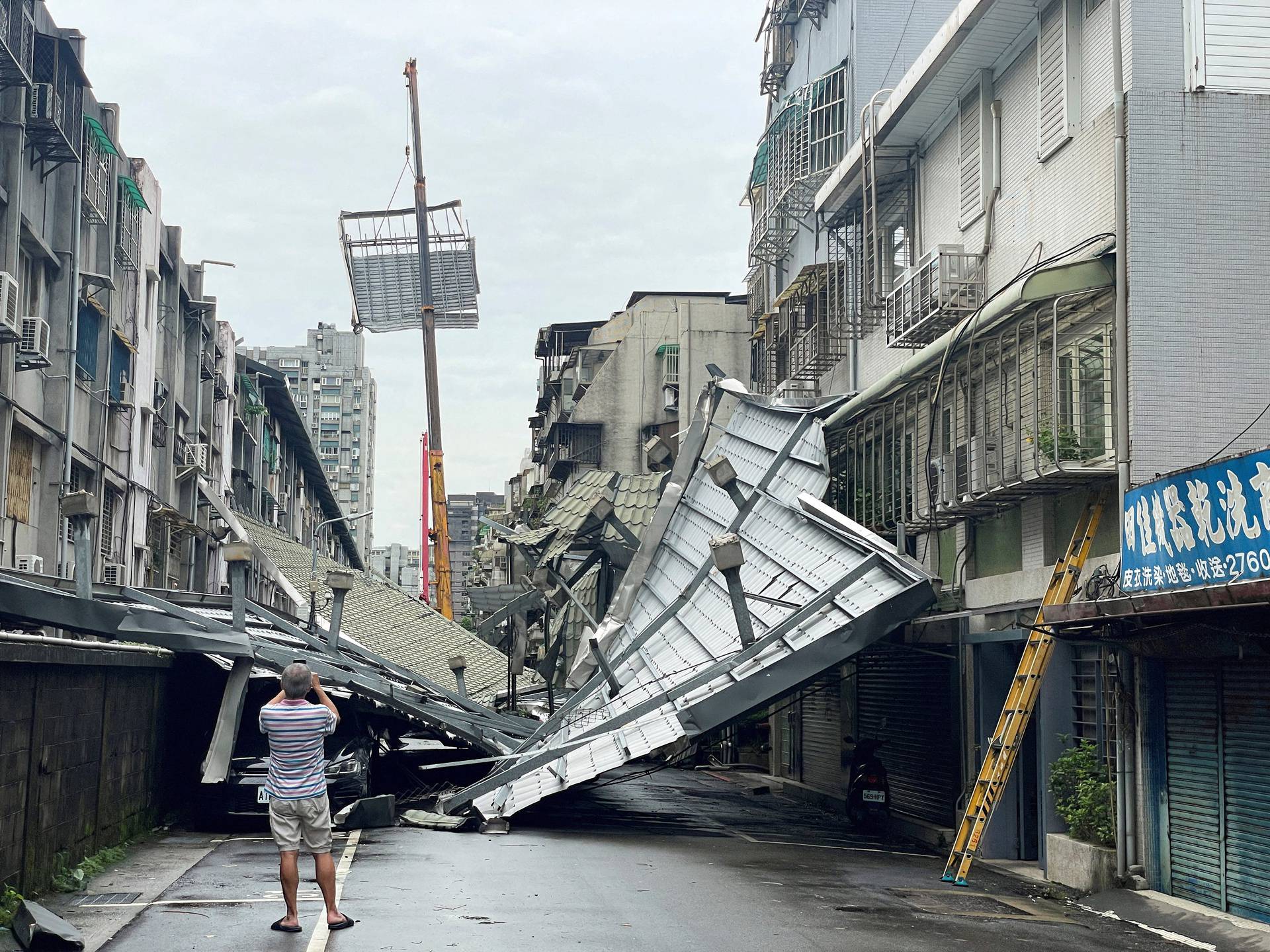 A man clicks pictures of a damaged rooftop after Typhoon Kong-rey made landfall in Taipei