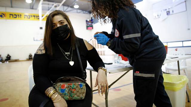 A woman is vaccinated against the coronavirus disease (COVID-19) at a temporary vaccination centre at a sports court in Tel Aviv