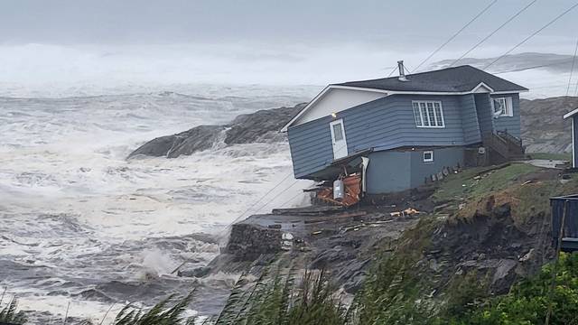 Waves roll in near a house built close to the shore as Hurricane Fiona passes Port aux Basques