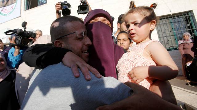 Freed Palestinian journalist Mohammad al-Qiq, who was detained by Israel last November and went on 94-day hunger strike to protest against his detention without charge, is hugged by his sister upon his release in the West Bank town of Dura