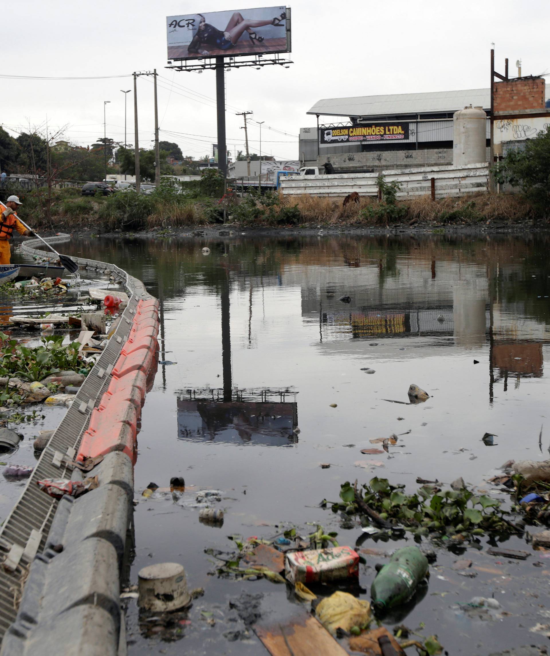 Men work cleaning up the garbage next to an ecobarrier at Meriti River which flows into Guanabara Bay, in Duque de Caxias, near Rio de Janeiro