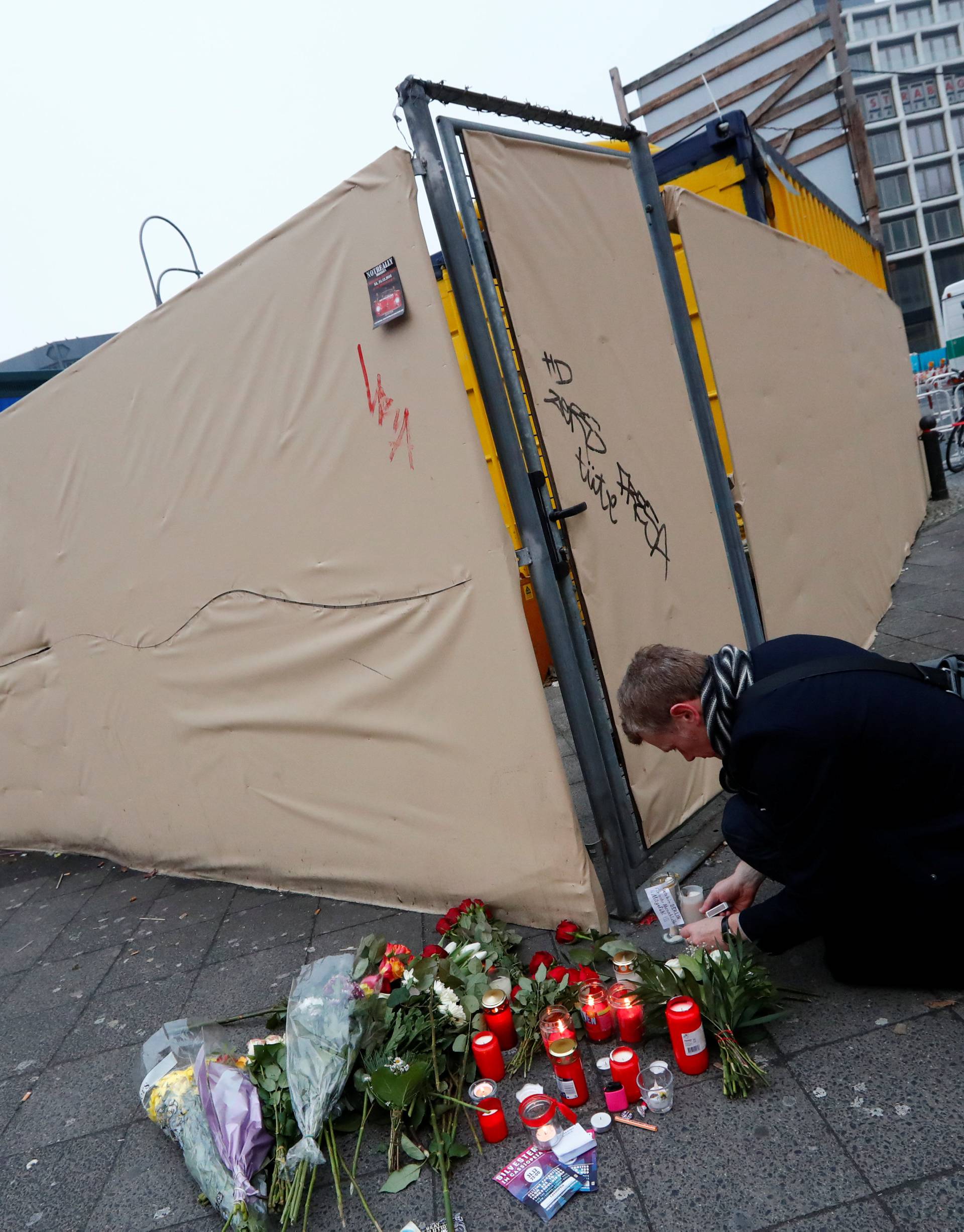 A man lights candles near the scene where a truck ploughed into a crowded Christmas market in the German capital last night in Berlin